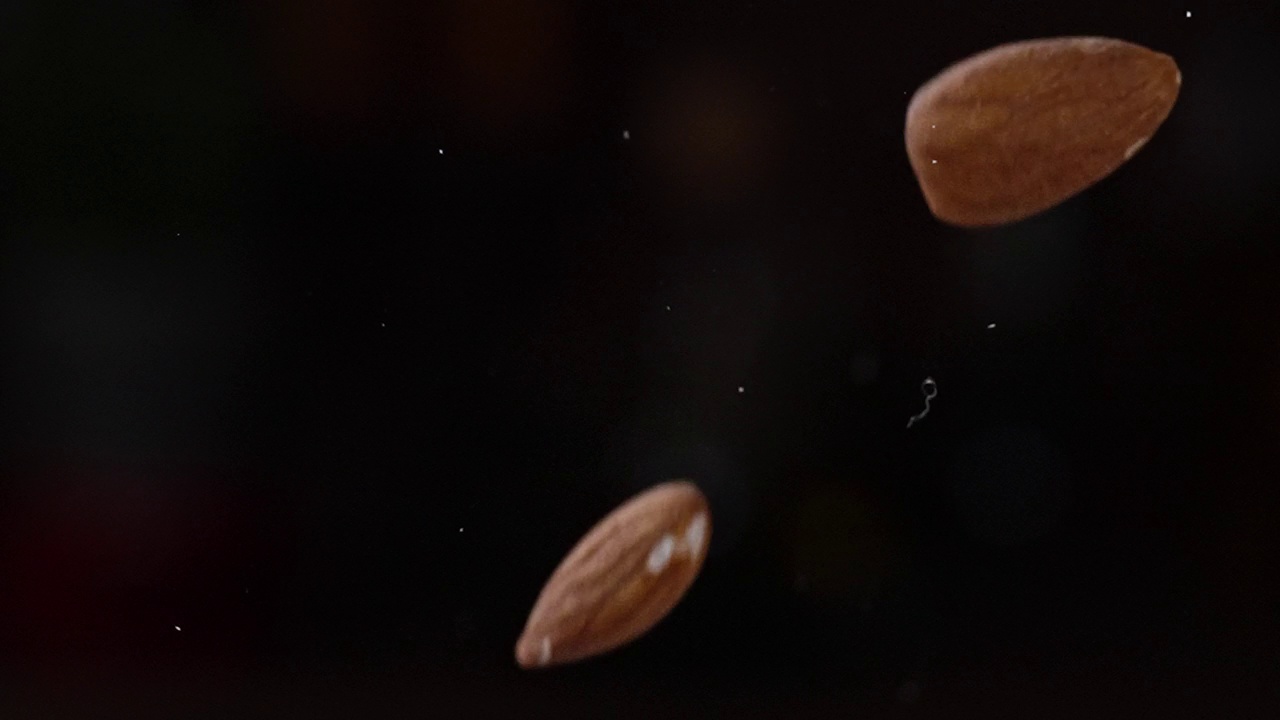 慢动作的杏仁种子落在黑暗的背景视频素材