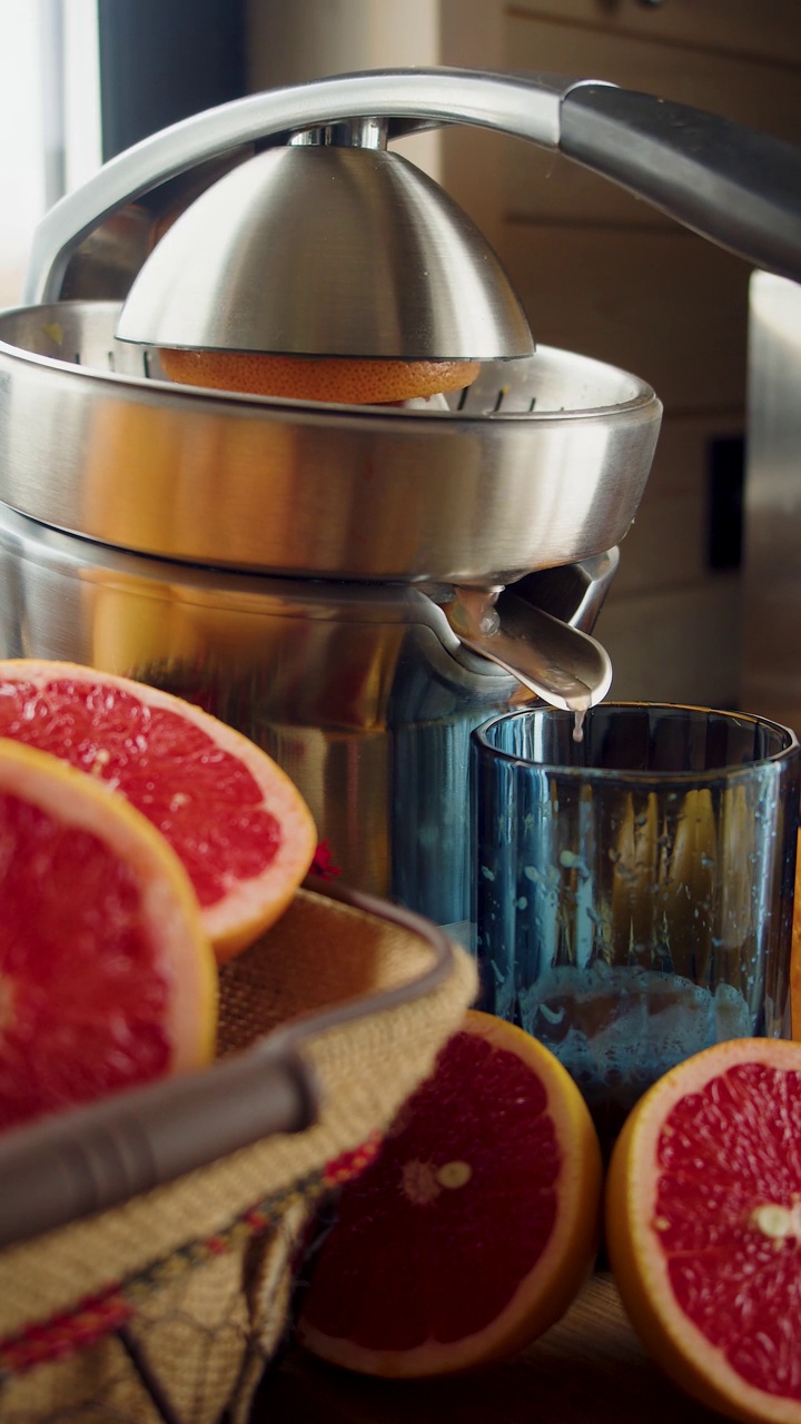 男性用榨汁机榨葡萄柚汁。特写镜头。垂直的画面。视频素材