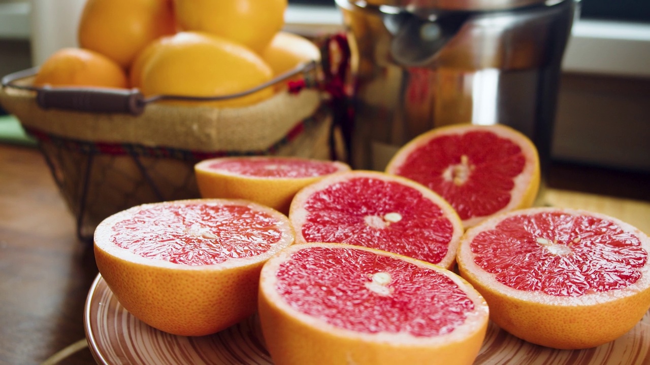 一盘切好的葡萄柚在榨汁机前旋转的特写镜头。健康食品和素食主义。视频素材