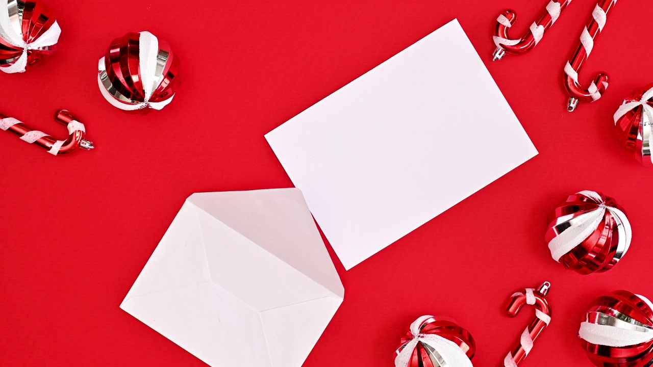 圣诞贺卡与纸来自信封上的红色背景与圣诞装饰品。停止运动视频下载