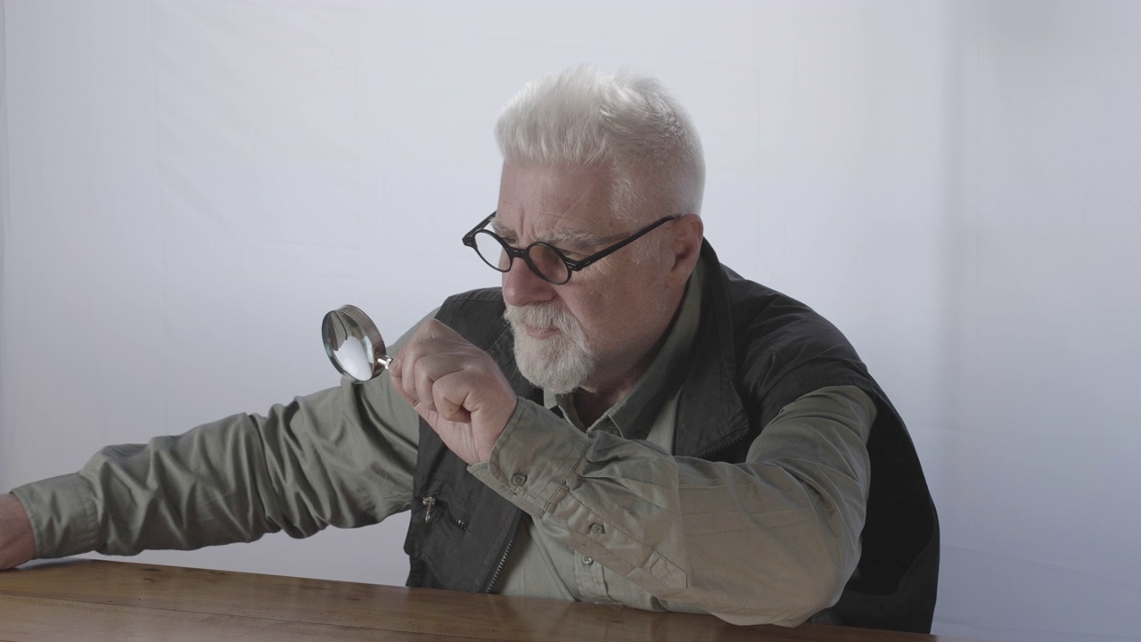 一位白种老人在两个放大镜的帮助下仔细观察视频下载