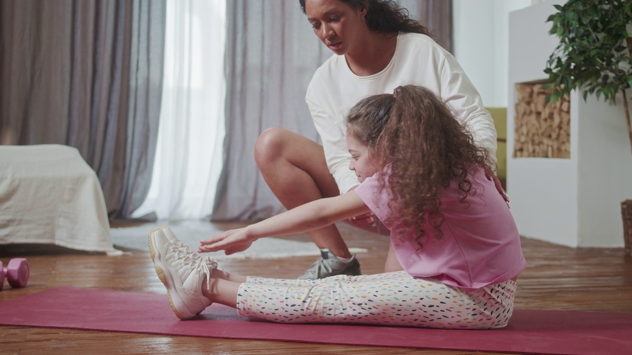妈妈和可爱的小女儿一起做拉伸运动，一起训练舒适的家。视频下载
