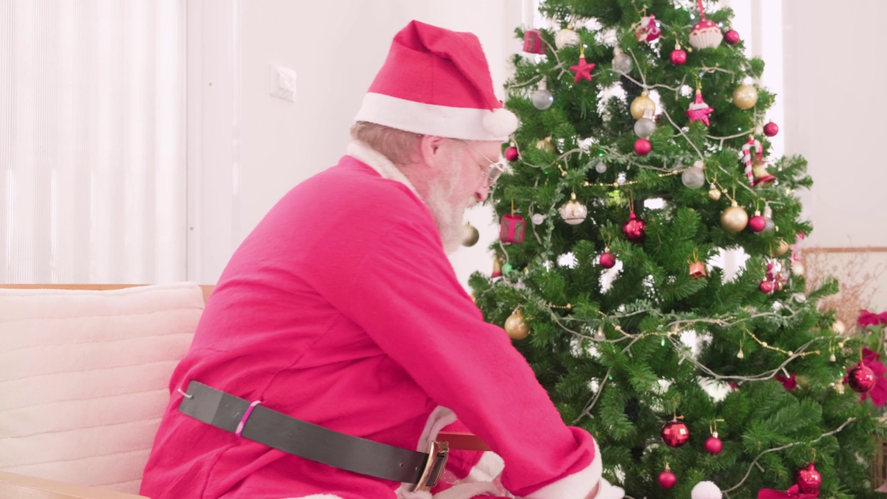 年迈的圣诞老人穿着圣诞服装，手持圣诞礼盒。视频下载