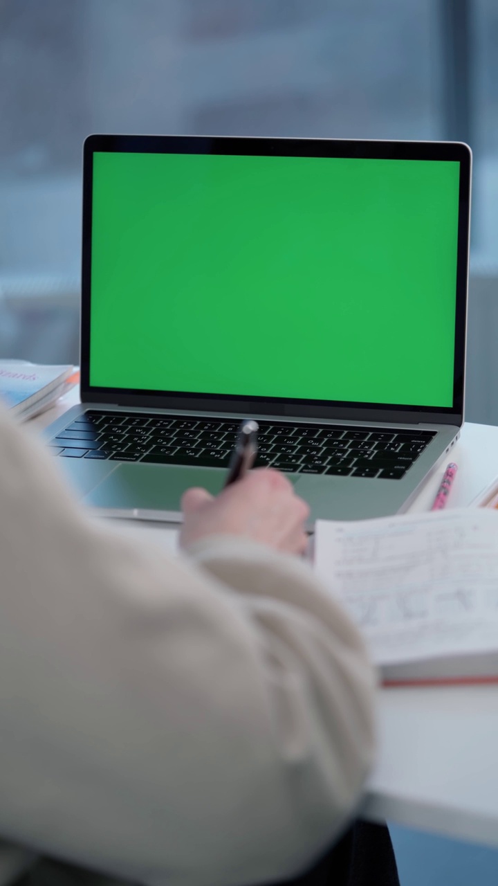 一名女子使用绿色屏幕的笔记本电脑。女学生在网上上课视频素材