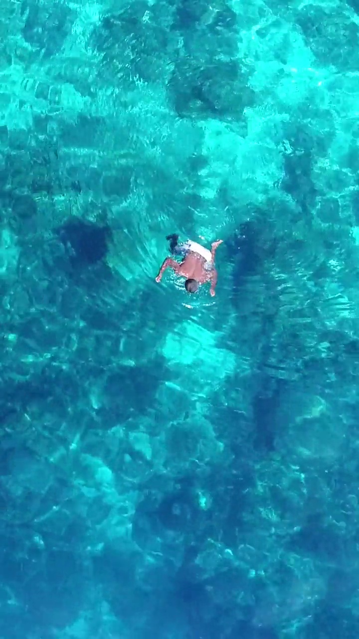 垂直视频的航拍浅珊瑚礁和蓝色的水与当地渔民视频下载