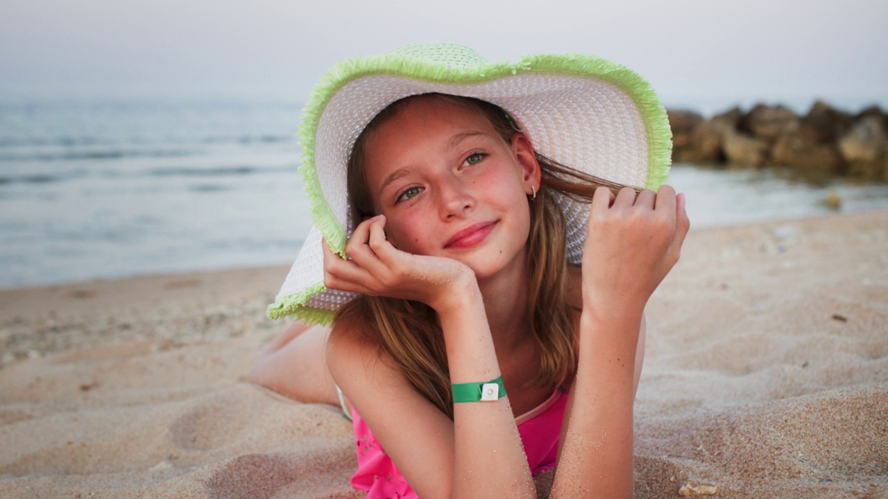 戴着帽子的少女躺在沙滩上做梦的肖像。视频下载