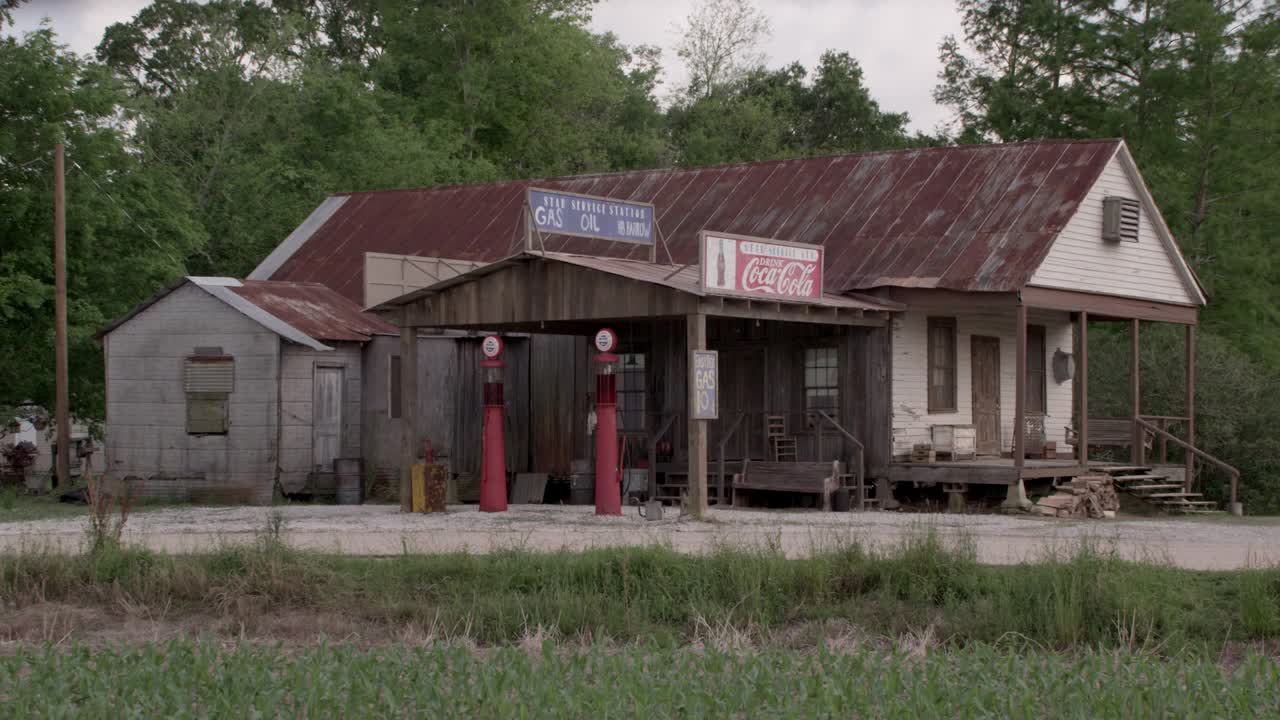 中间角度的加油站有可口可乐的标志，古色古香的加油站在木隔板建筑前。可能是一家杂货店视频下载