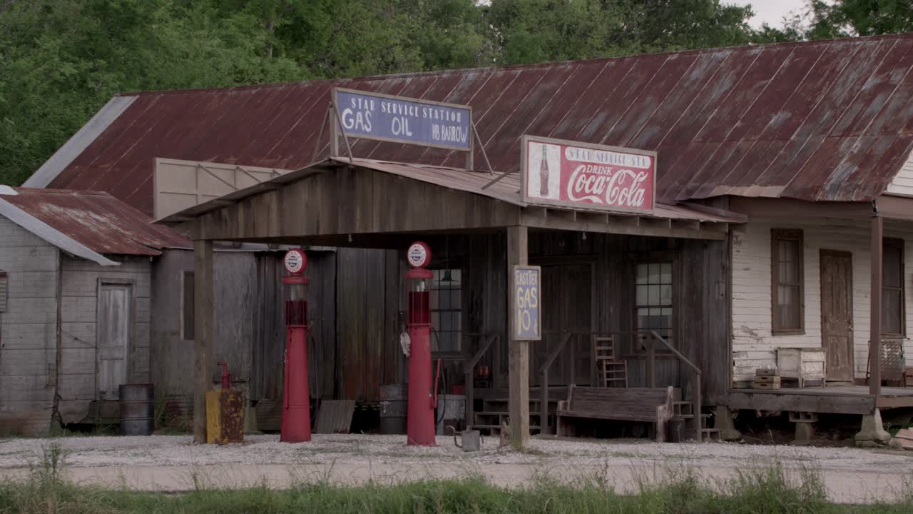 中间角度的加油站有可口可乐的标志，古色古香的加油站在木隔板建筑前。可能是一家杂货店视频素材