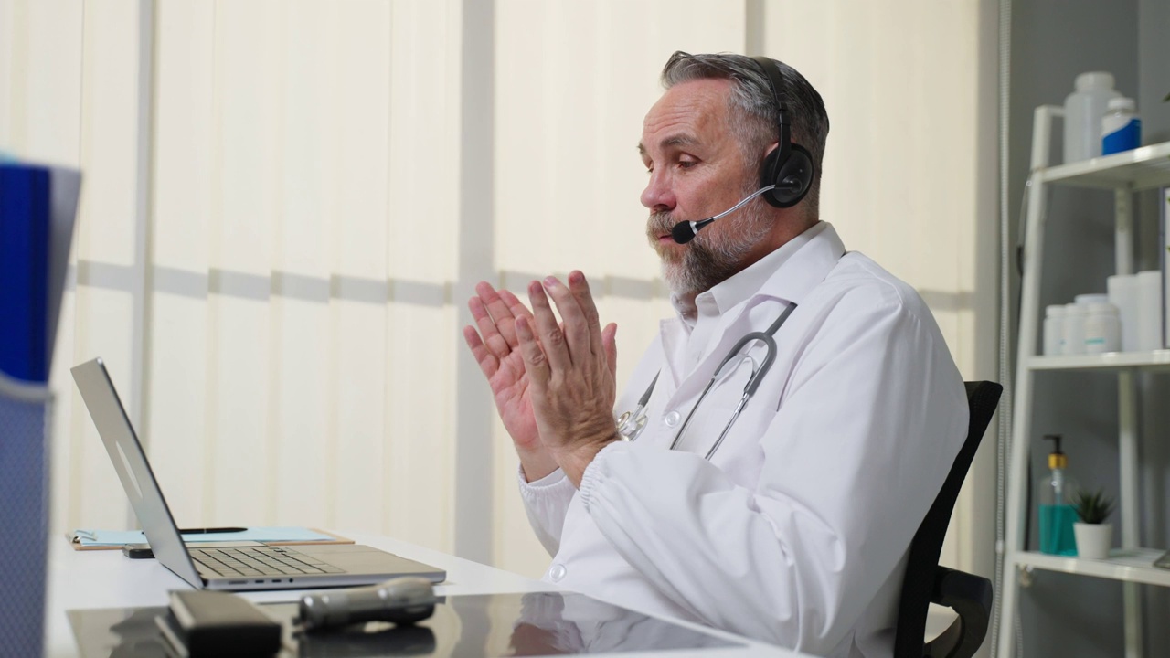 白人男性医生与患者在线虚拟对话。有吸引力的老年成熟医生远程工作，从办公室医院和广播诊断治疗患者远程健康。视频素材
