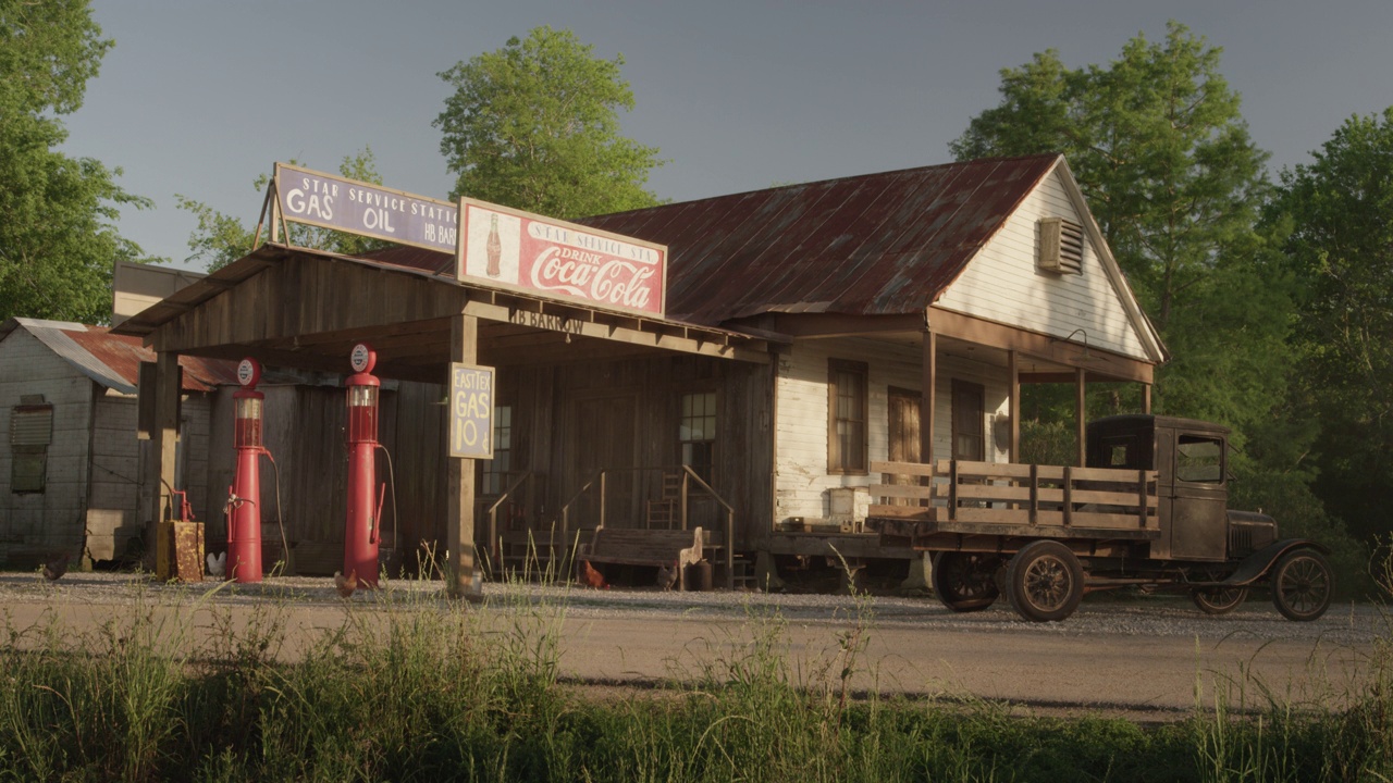 一个老式加油站的广角，有可口可乐的标志，加油站，一辆老式卡车，还有一个写着“星级加油站汽油手推车”的标志。一辆老爷车驶过时，鸡在地上啄来啄去视频下载