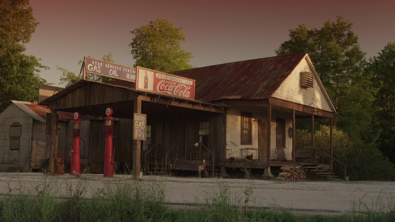一个老式加油站的广角，有可口可乐的标志，加油泵，还有一个写着“星级加油站汽油手推车”的标志。鸡啄地视频下载