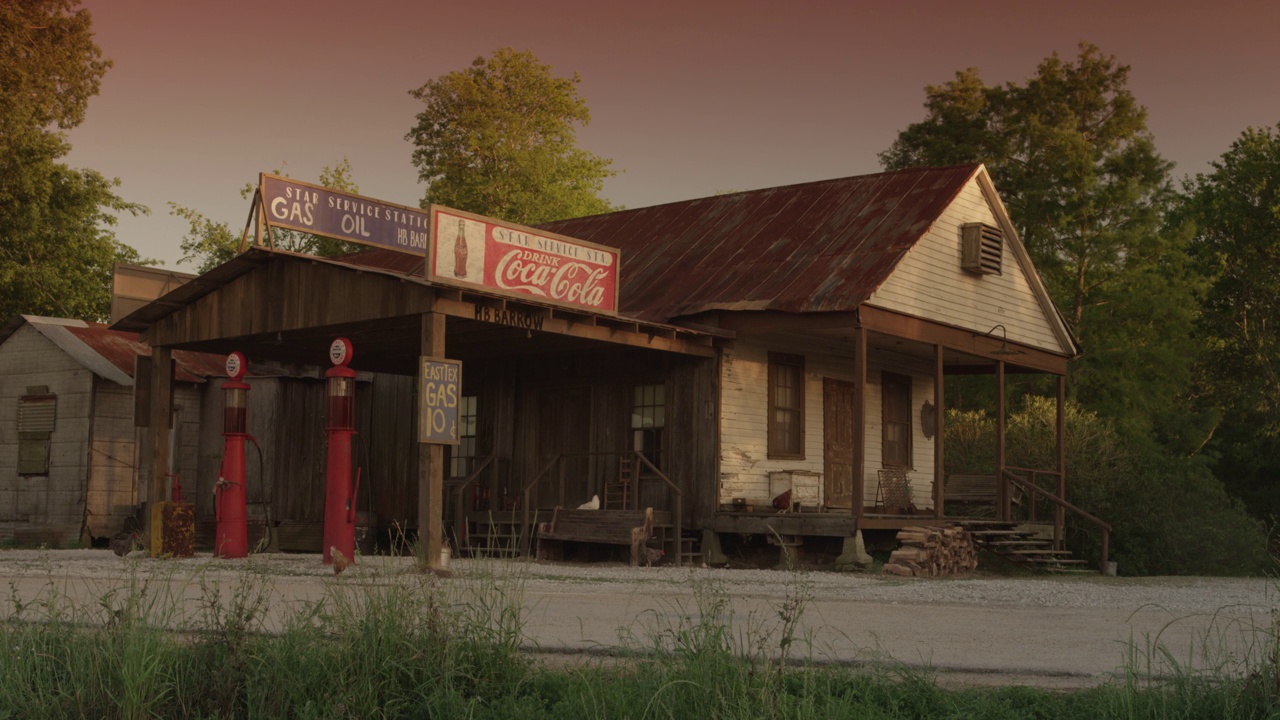 一个老式加油站的广角，有可口可乐的标志，加油泵，还有一个写着“星级加油站汽油手推车”的标志。鸡啄地视频下载