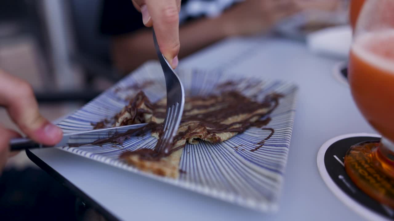 Teenage boys having crepes with chocolate in a sidewalk café视频素材