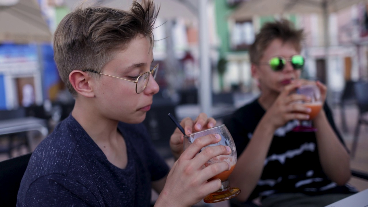 十几岁的男孩在路边咖啡馆喝冰沙视频素材