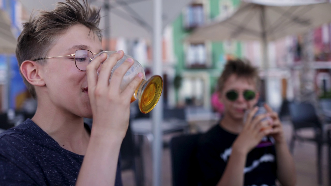 Teenage boys drinking smoothies in a sidewalk café视频素材