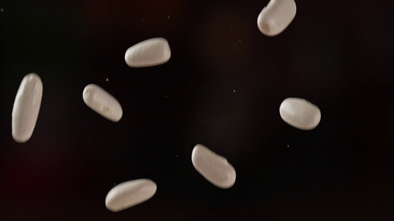 白豆落在黑暗背景上的慢动作视频下载