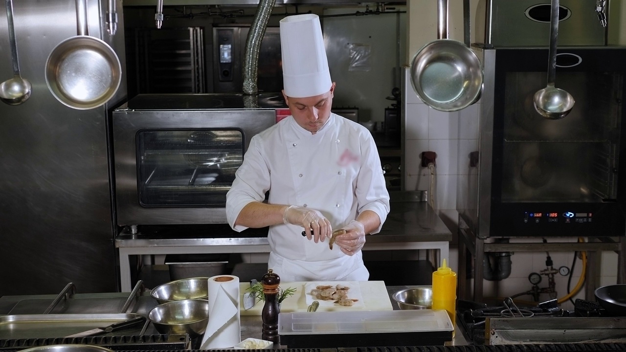 厨师在餐厅厨房用刀剥一只大虾。视频下载
