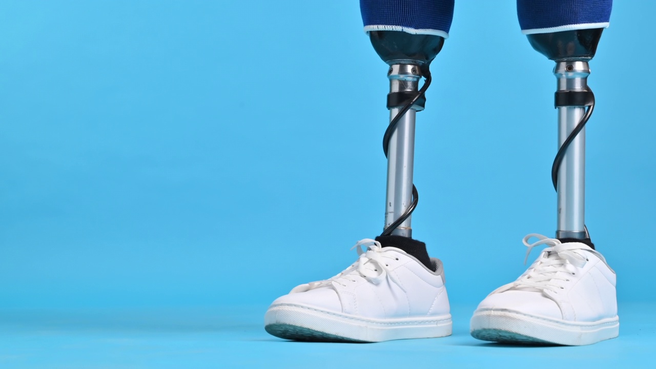 一个男人的假腿和白色运动鞋行走，蓝色背景视频下载