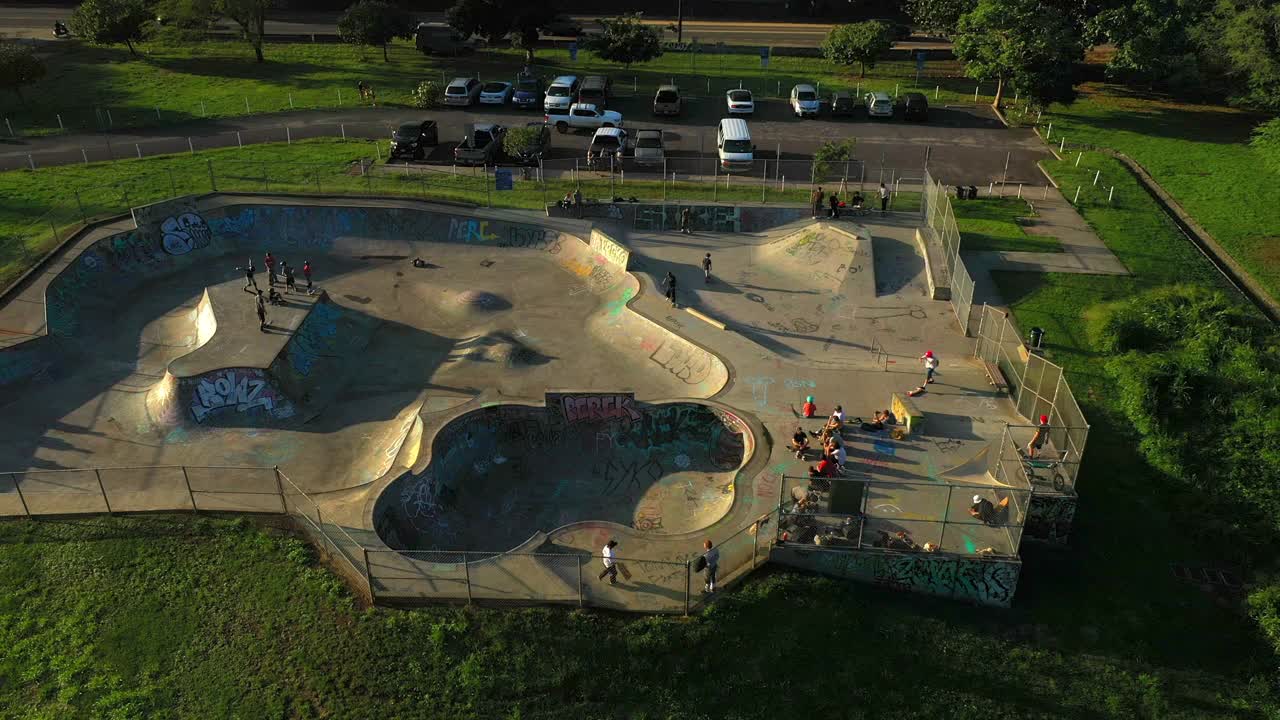 空中平移拍摄的人在滑板公园的停车场在日落-瓦胡岛，夏威夷视频下载