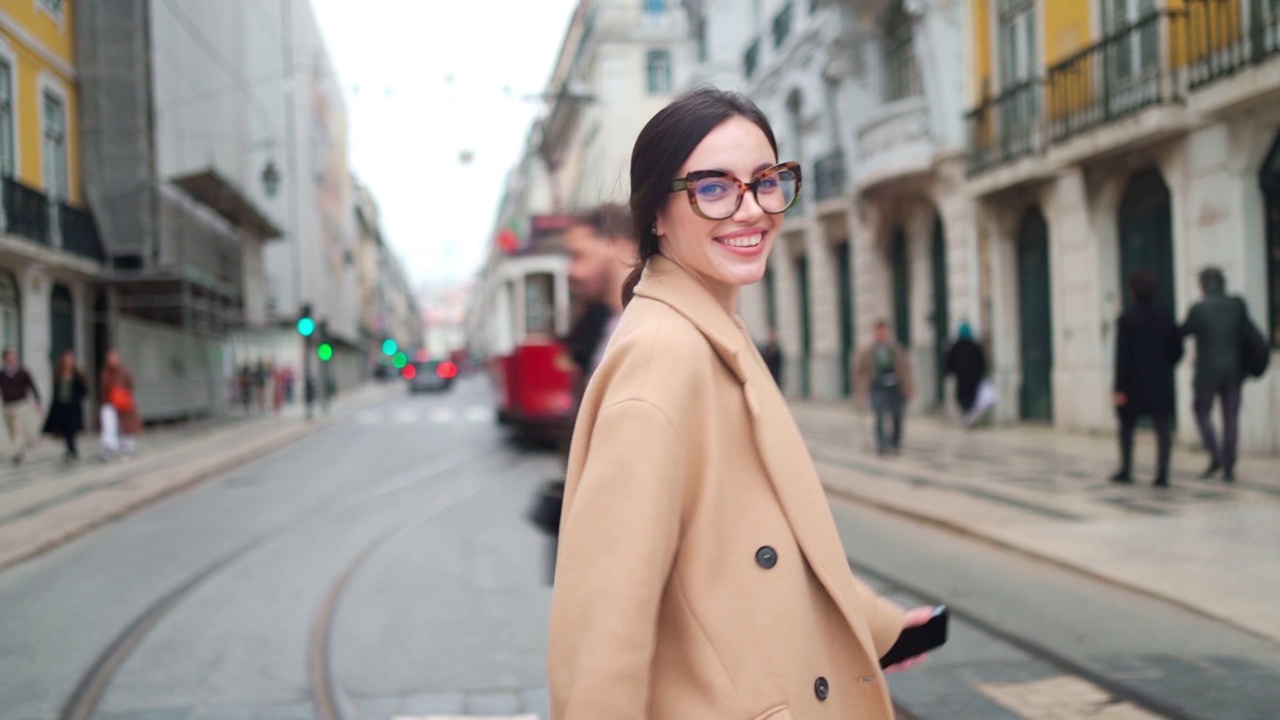 戴眼镜穿着外套的女人走在城市街道的人行横道上视频素材