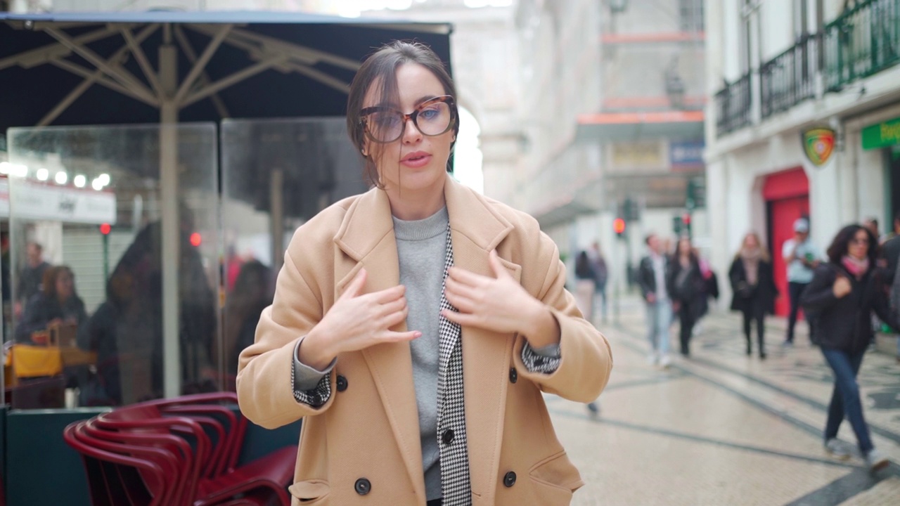 戴眼镜的女人穿着外套走在城市街道上视频素材