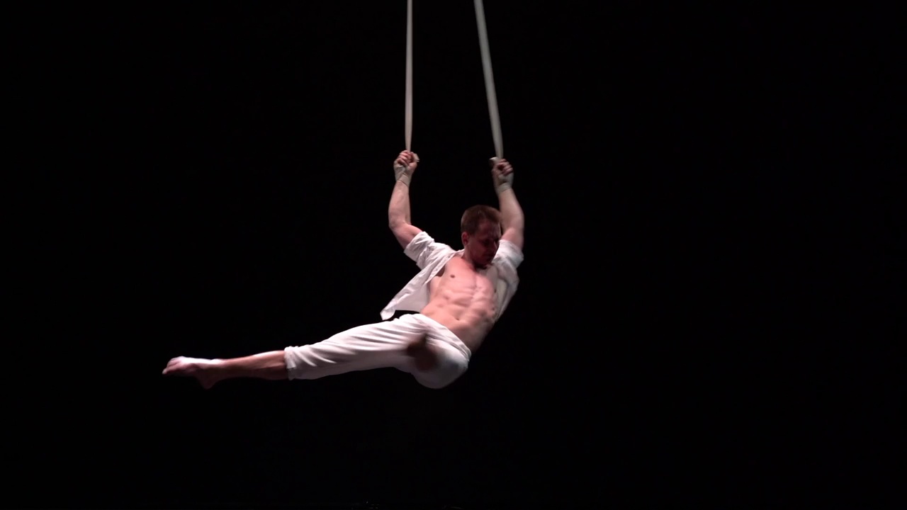 男性肌肉马戏团艺术家在空中做强大的特技绑带在黑色背景视频下载