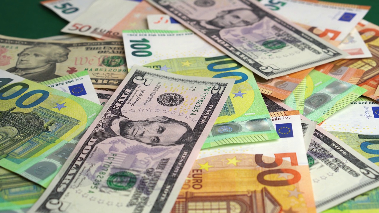 钱掉在桌子上。掉落大量的欧元和美元纸钞在绿色背景视频下载