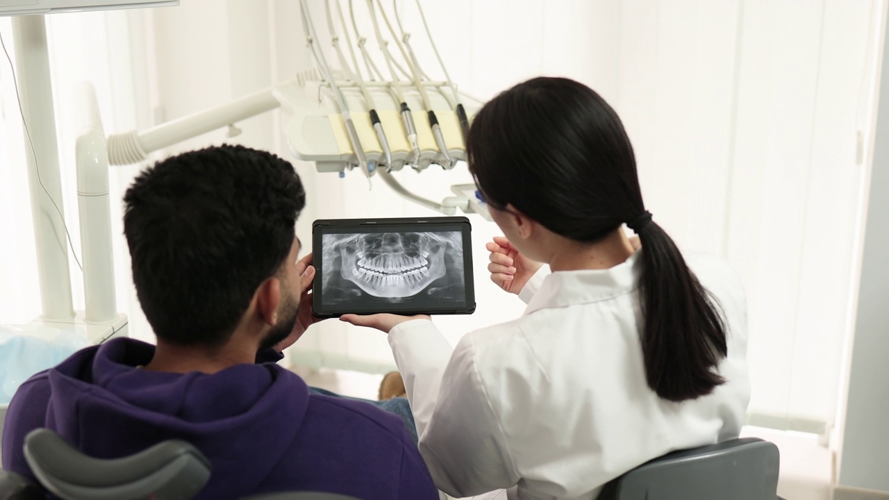 年轻的亚洲女牙医持有x光图像。视频下载