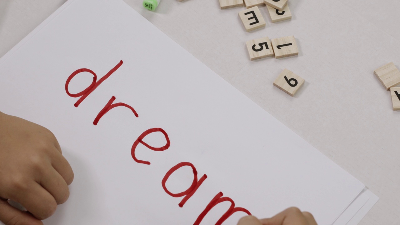 一个孩子写在纸上的单词DREAM。视频下载