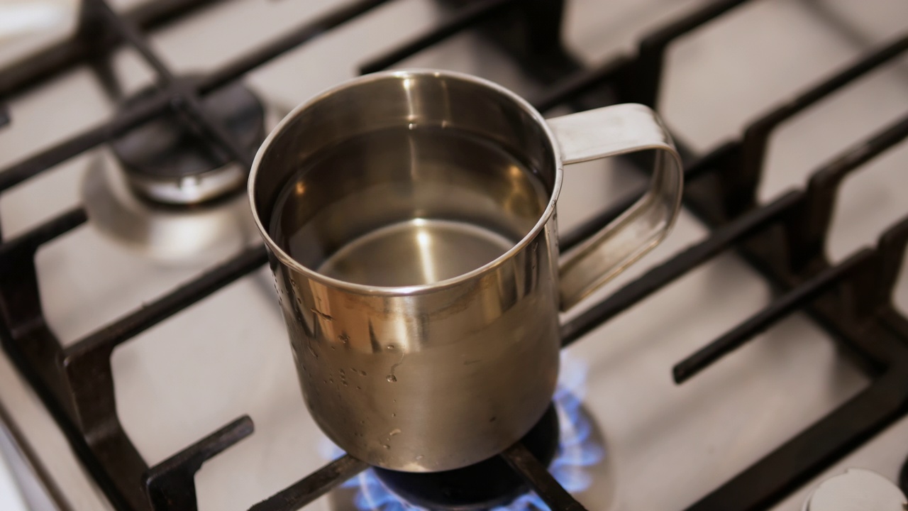 用金属杯烧水。一杯水放在煤气炉上。乌克兰电力不足，使用天然气视频素材