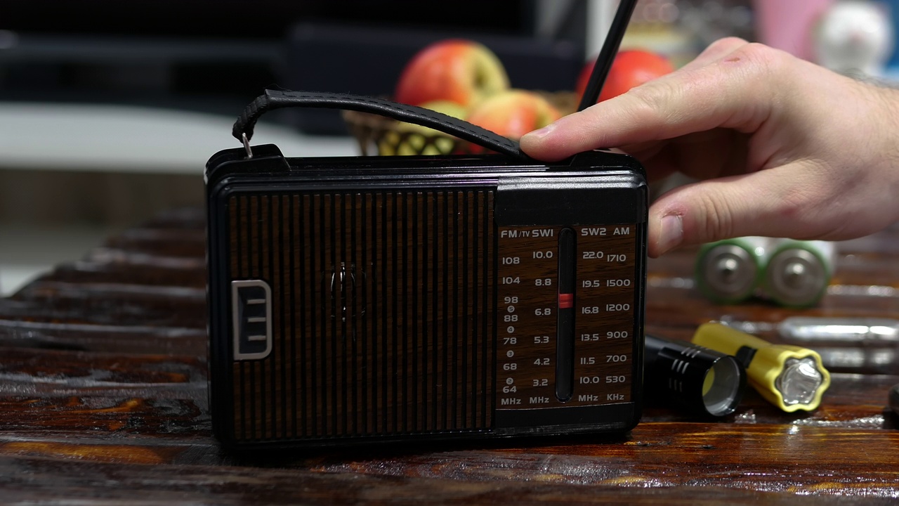 一名男子在一张旧木桌上用收音机收听无线电波。带天线的古董接收机。把模拟收音机调到一个音阶上。一个男人在用一台旧收音机听新闻。听音乐视频素材