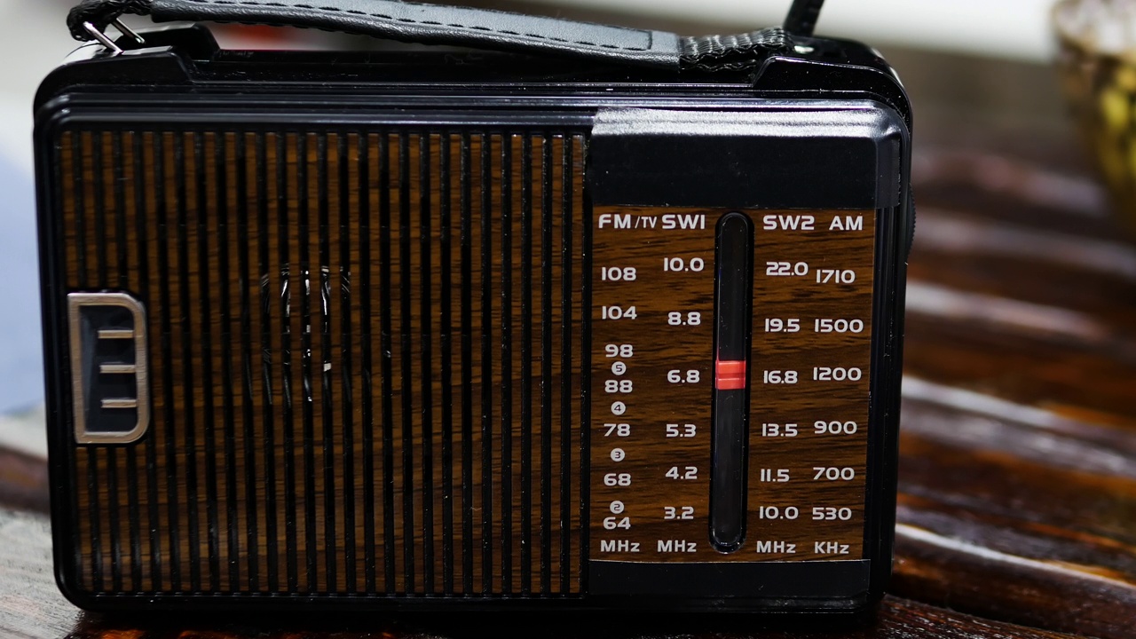 一名男子在一张旧木桌上用收音机收听无线电波。带天线的古董接收机。把模拟收音机调到一个音阶上。一个男人在用一台旧收音机听新闻。听音乐。视频下载