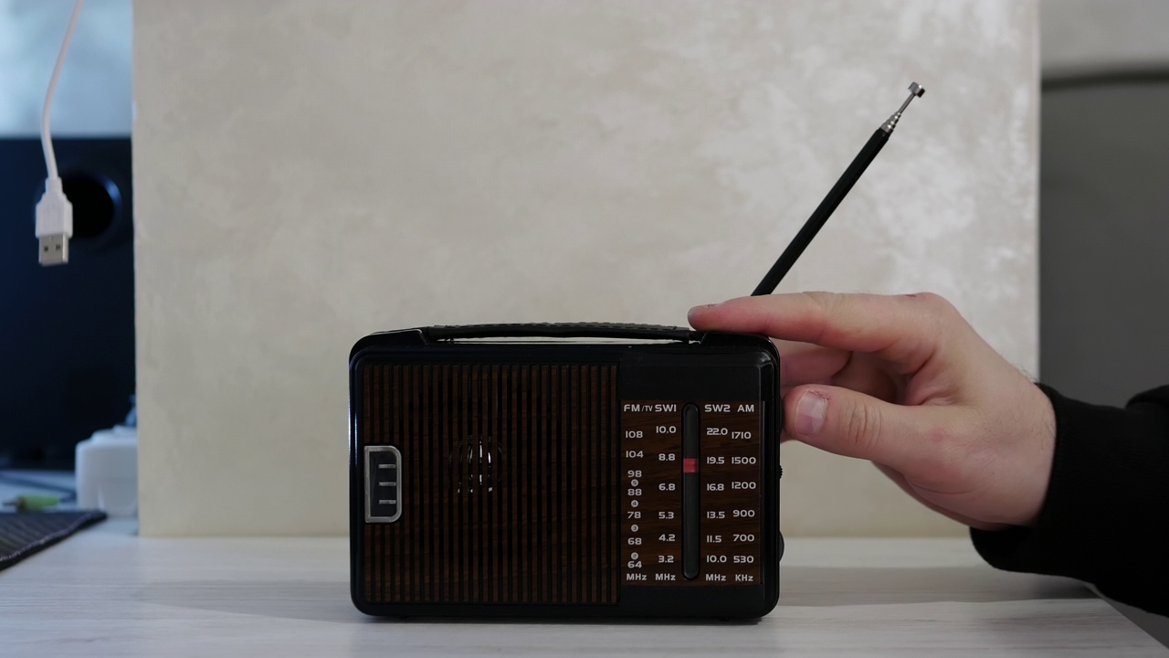 一个男人的手在一张旧木桌上调收音机里的无线电波。带天线的古董接收机。的生活方式。把模拟收音机调到一个音阶上。一个男人在用一台旧收音机听新闻。听音乐视频素材