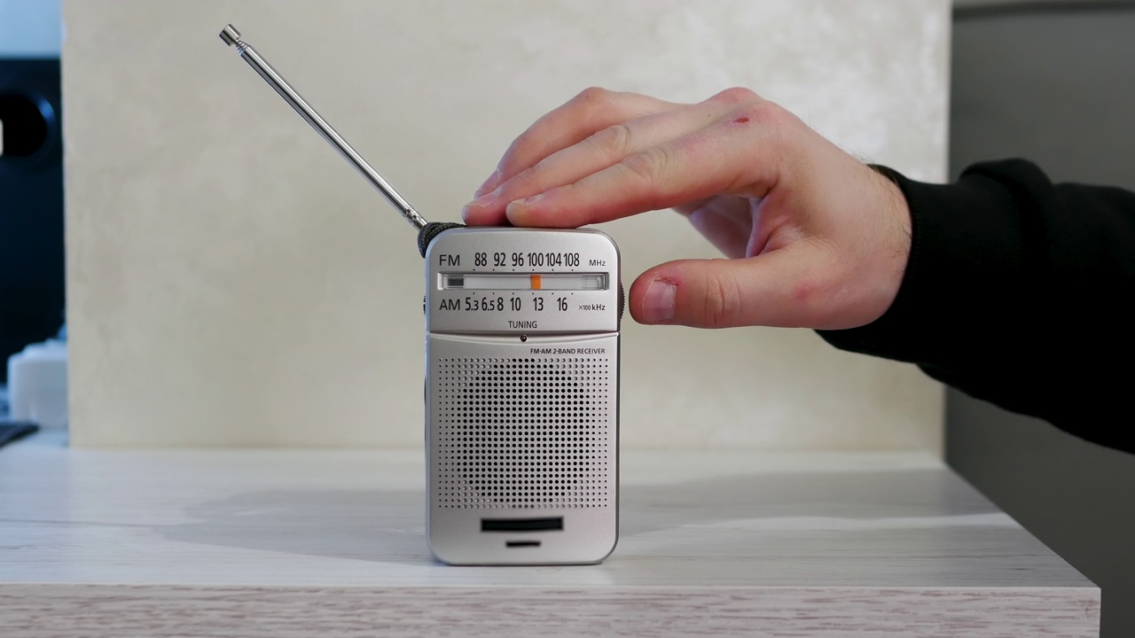 一个男人的手在一张旧木桌上调收音机里的无线电波。带天线的古董接收机。怀旧的生活方式。把模拟收音机调到一个音阶上。一个男人在用一台旧收音机听新闻。听音乐视频素材