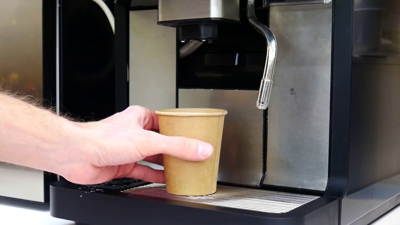 一个咖啡机和一个男人用纸板杯煮咖啡的特写镜头视频下载