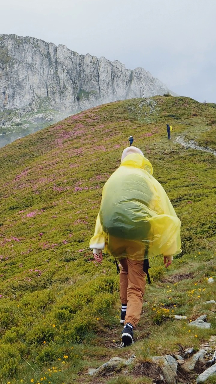 穿着雨衣走在山边的女人视频素材
