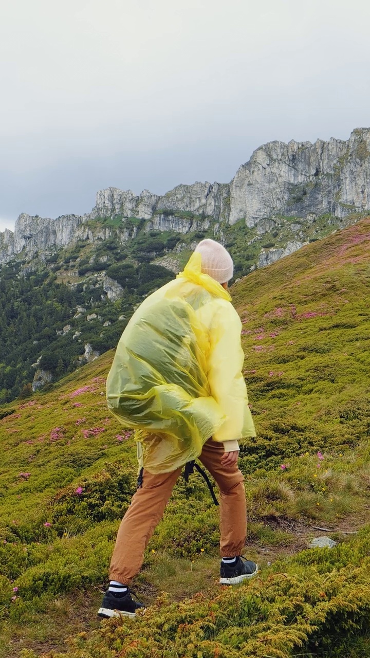 身穿黄色雨衣的女子径直走向山顶视频素材