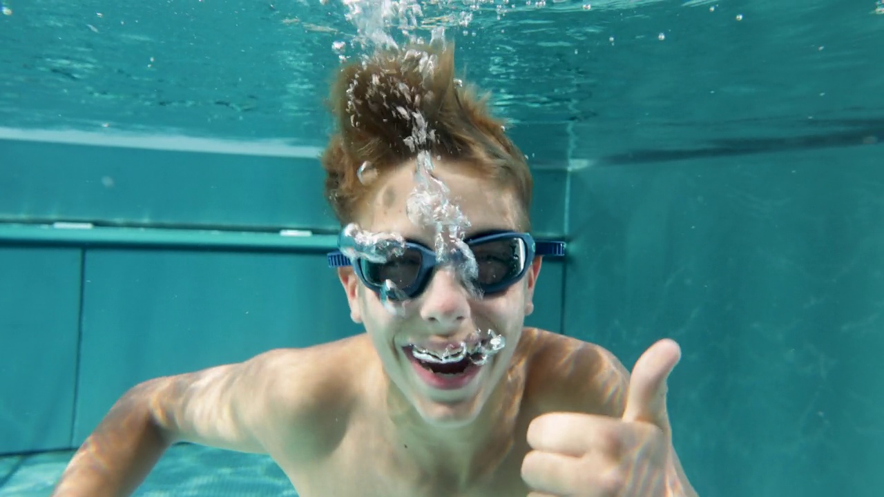 一个十几岁的男孩在游泳池里游泳的肖像视频下载