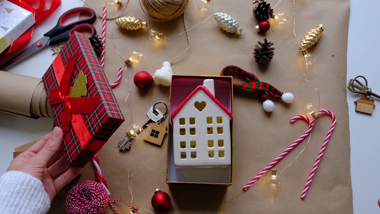 钥匙的房子与钥匙链上舒适的家在礼盒与圣诞装饰包装。为新年、圣诞节打包礼物。建筑，项目，搬新房，抵押，租赁，购买房地产视频素材