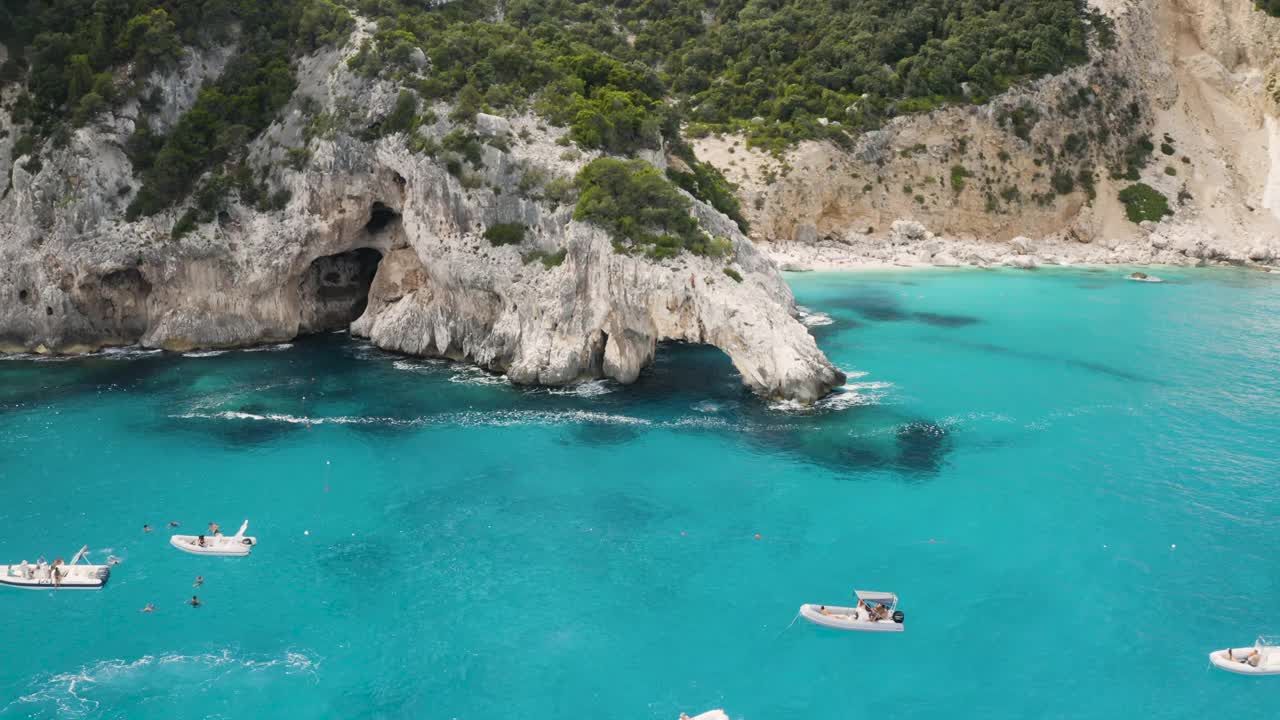 飞过美丽的海洞和清澈的蓝色翡翠水与船的顶部视图。夏季海景鸟瞰图。意大利撒丁岛视频素材