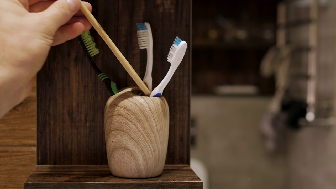 把牙刷放在浴室的盒子里。一名男子用他的手放置一个木制的环保牙刷来刷牙视频素材