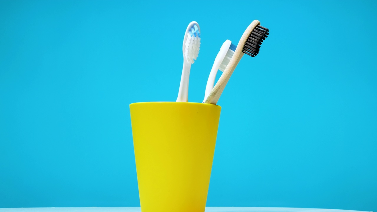 一套牙刷在转盘上旋转，背景是蓝色的。黄色塑料盒里的牙刷。视频素材