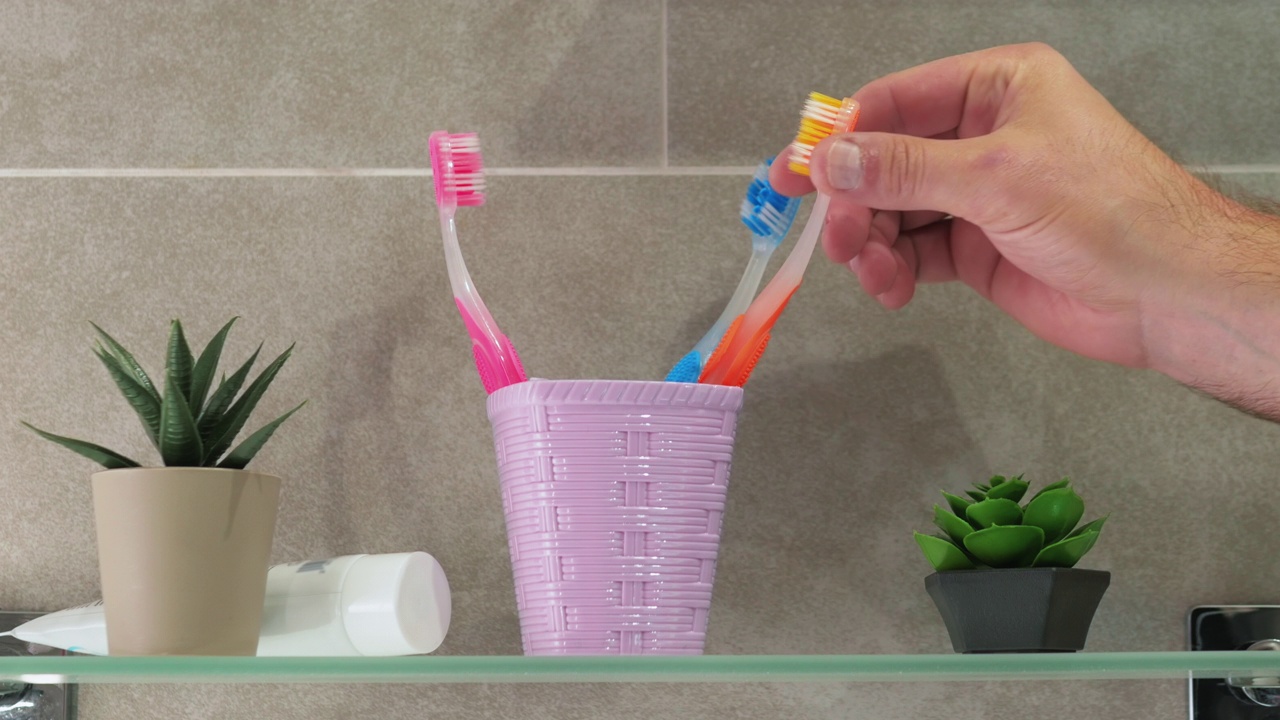 用手拿着牙刷，白牙的概念，一个男人在浴室里刷牙视频素材