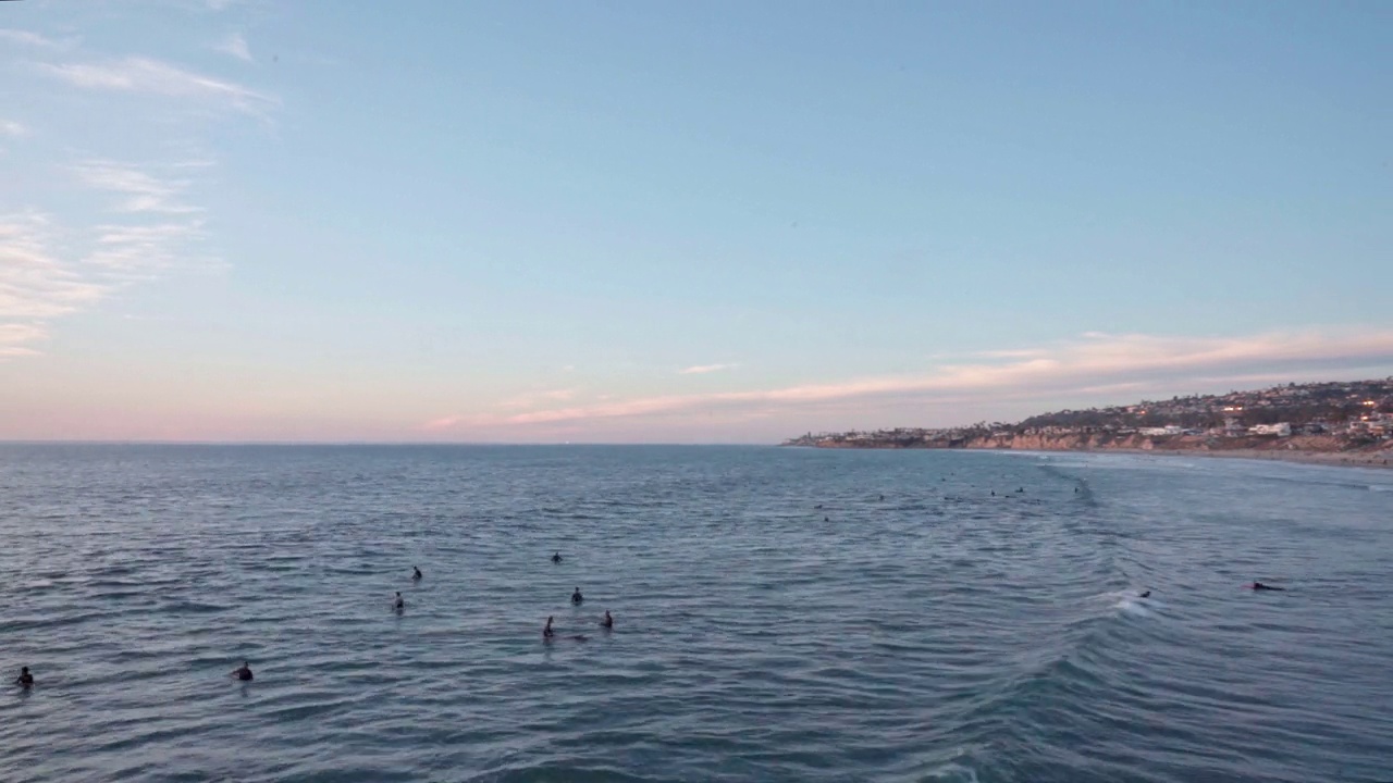 在圣地亚哥太平洋海滩的水晶码头，冲浪者在日落时捕捉晚潮的高角度视图延时视频下载