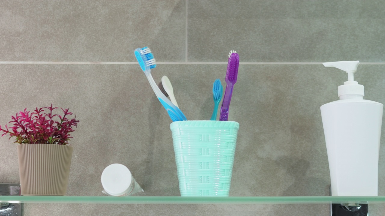 浴室里牙刷的定格动画。健康牙齿的概念。浴室玻璃架子上五颜六色的牙刷视频下载