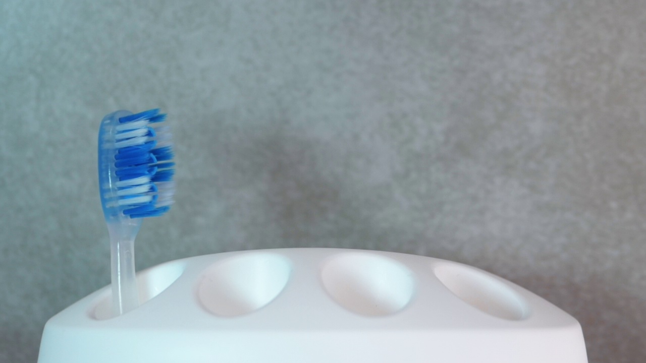 柔软的蓝色牙刷在白色的情况下出现运动。牙科保健。健康牙齿的概念。在浴室刷牙。手里拿把牙刷视频素材