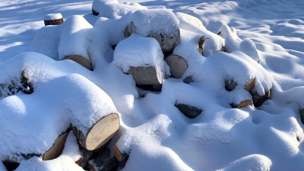 冬天的背景纹理图案与堆叠干燥的砍柴原木覆盖着雪。一堆木头被砍了。木堆上的雪。视频下载