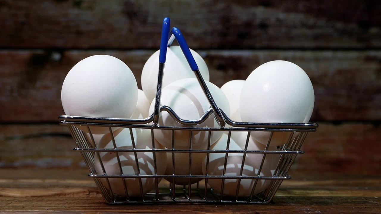 木制背景的超市手推车里的鸡蛋。杂货店里篮子里的鸡蛋的定格动画视频下载