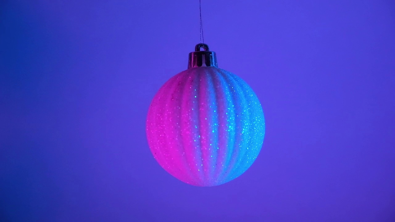 霓虹灯下的圣诞舞会。2023年新年。球挂在蓝粉红色的背景。圣诞快乐视频下载