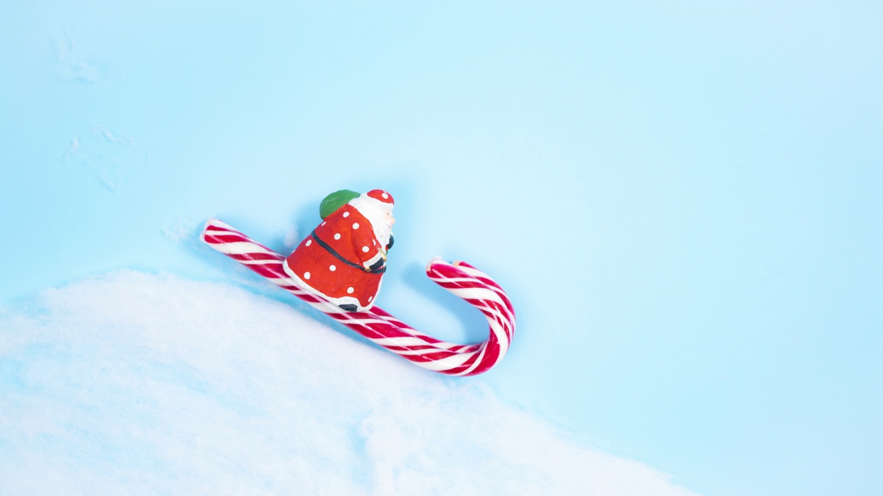圣诞老人驾着装满糖果的雪橇，从云层下沿着雪山的斜坡疾驰而来。蓝色背景。视频下载